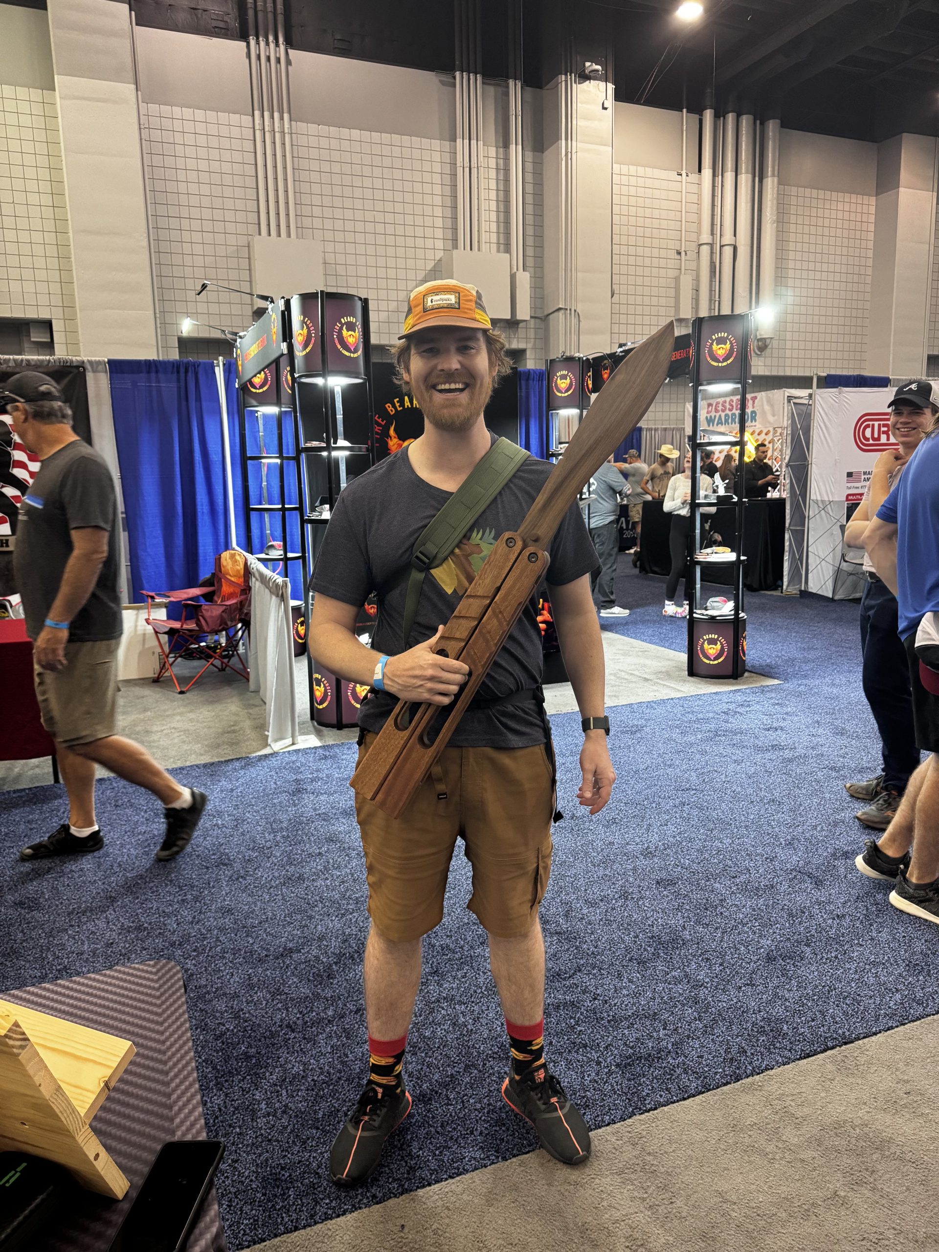 Llama Tom at Blade Show East holding a giant wooden balisong